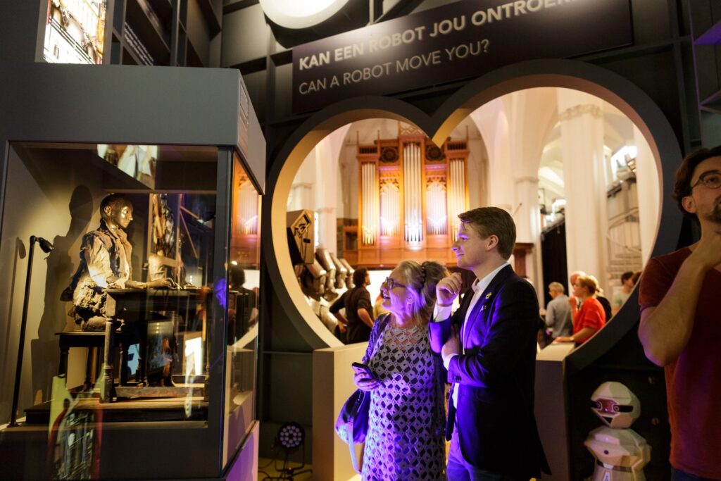 Bezoekers kijken naar muziekrobots in Robots Love Music