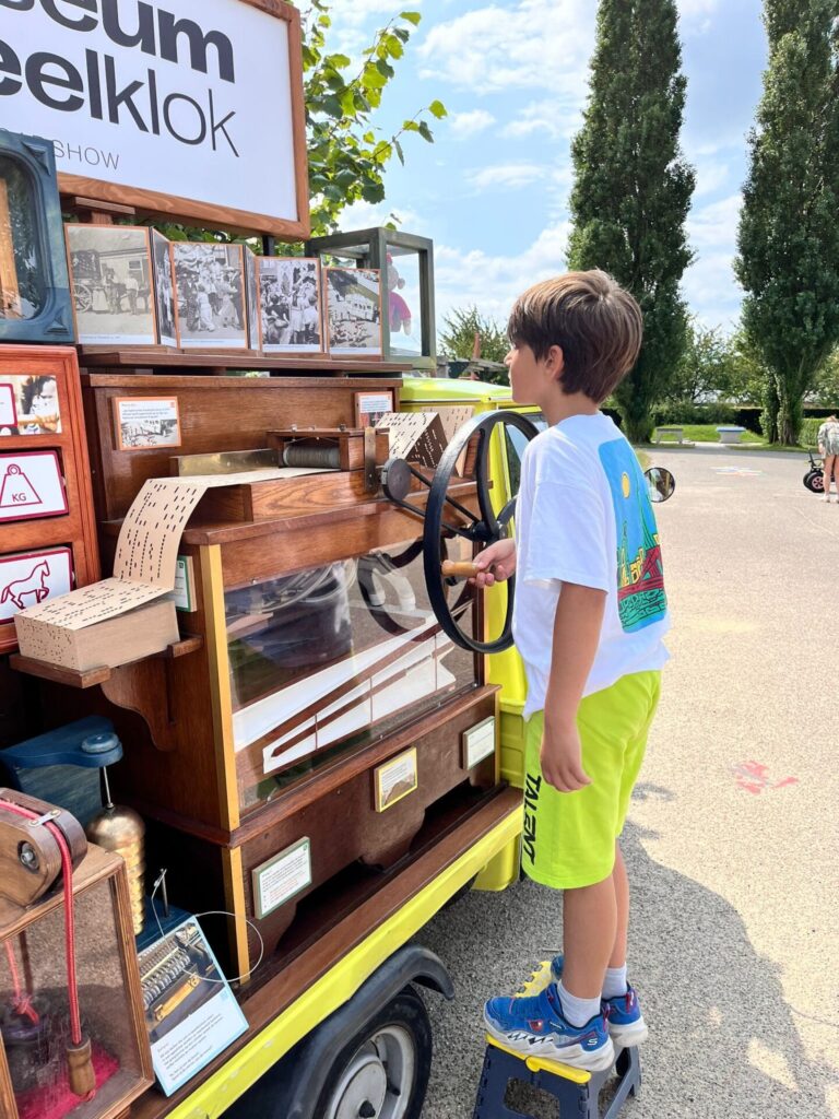 Een jongen draait aan het orgeltje van de Speelklok Roadshow