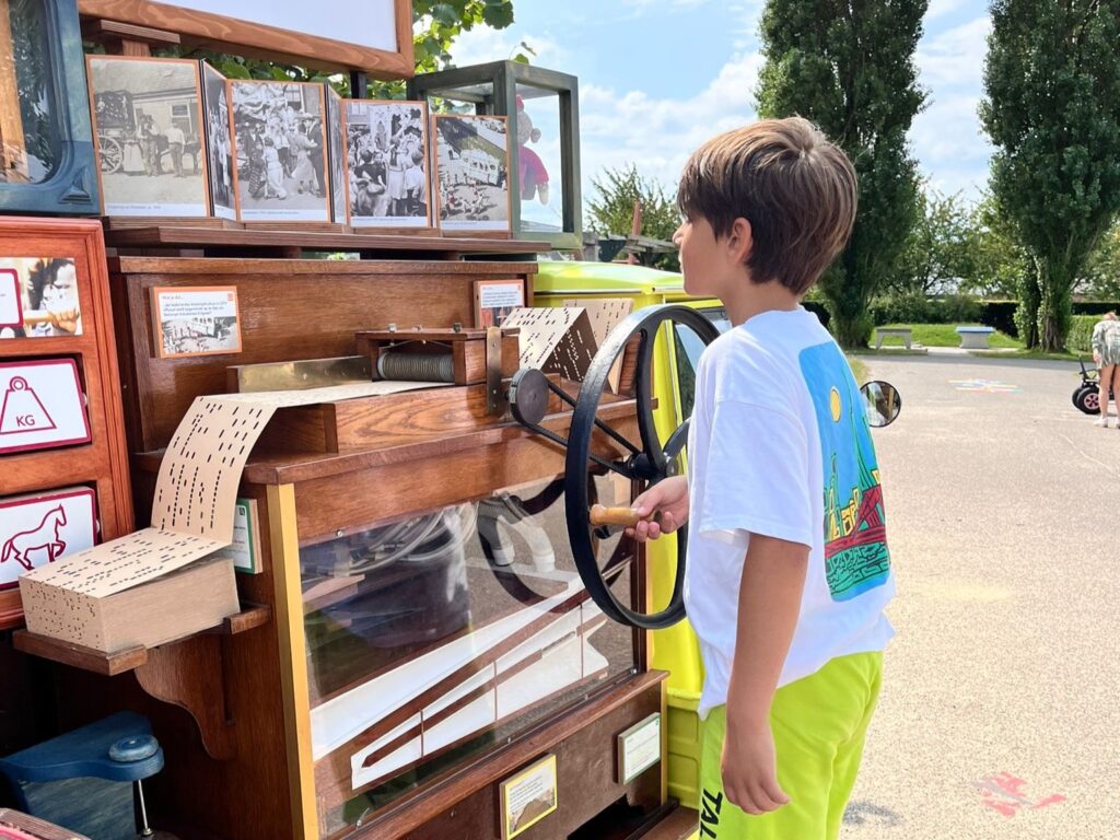 Een jongen draait aan het orgeltje van de Speelklok Roadshow